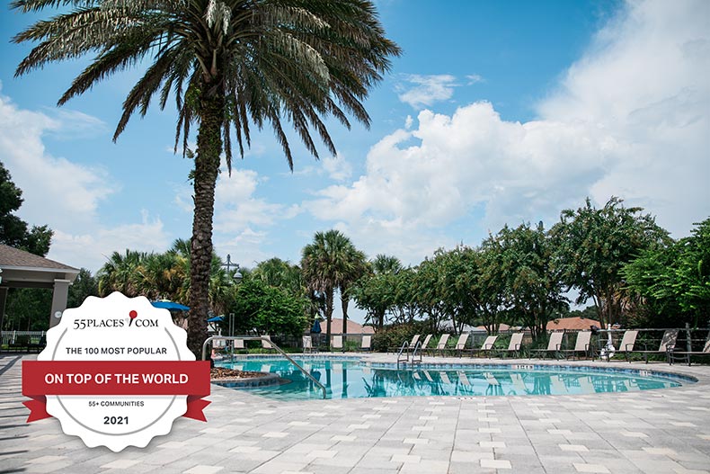 "The 100 Most Popular 55+ Communities" badge over an outdoor pool at On Top of the World in Ocala, Florida