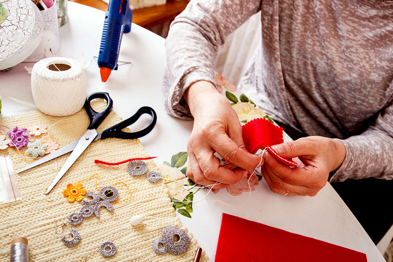 A woman sews a decoration in an arts studio.