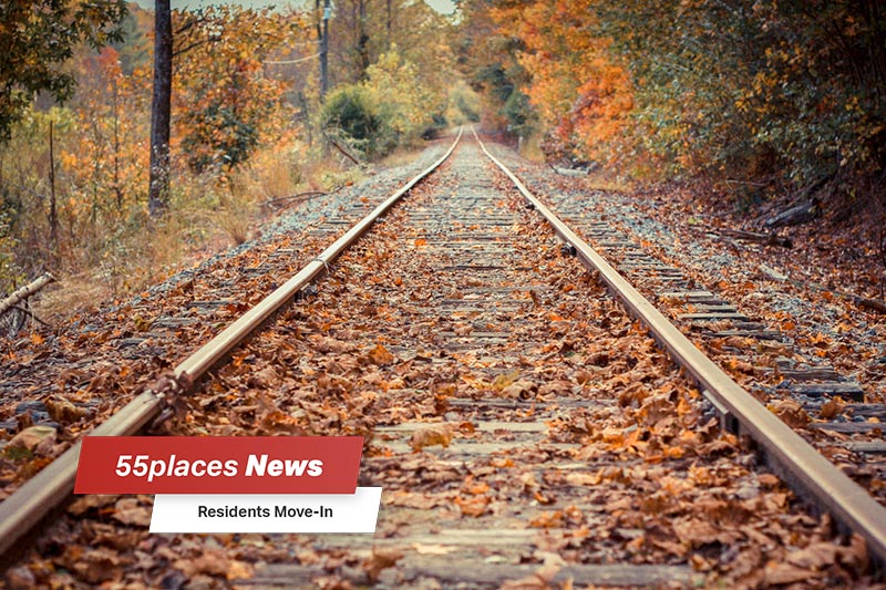 "55places News: Residents Move-In" banner over railroad tracks through the autumn woods in Blue Ridge, Georgia