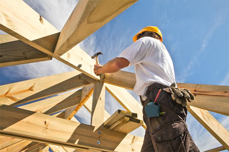 A carpenter working on a roof structure at a construction site