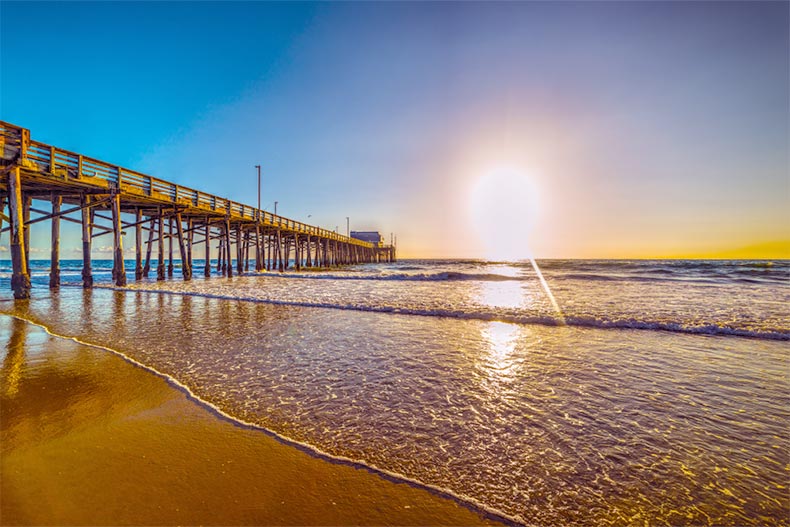 Sunset over a wooden pier extending into the ocean in Newport Beach, California