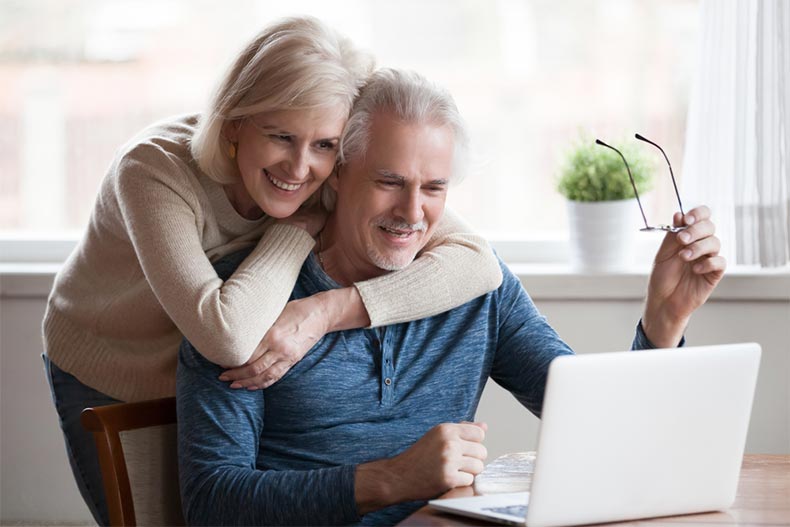 Senior couple smiling while using laptop together