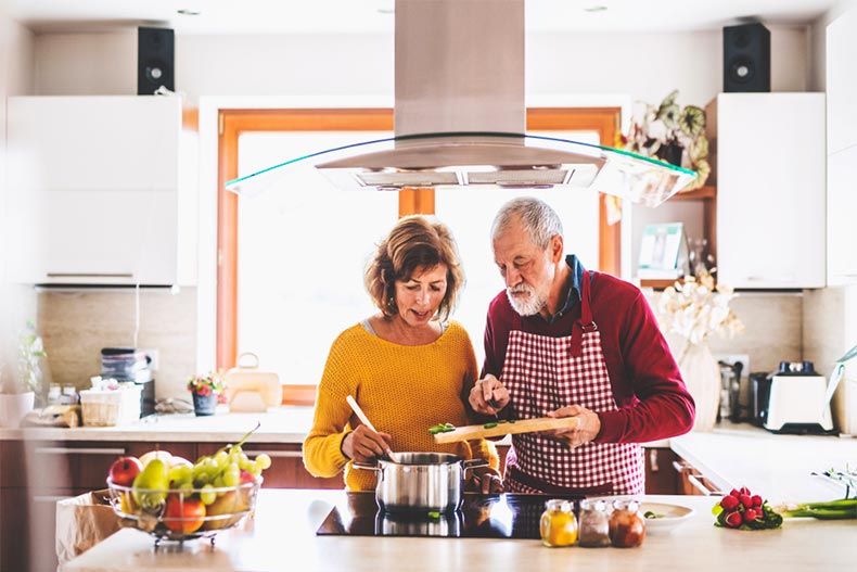 Older couple cooking over a stove in modern kitchen