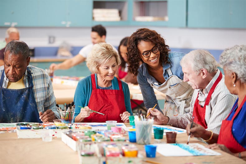 A group of retired seniors attending an art class at the amenity center in their 55+ community