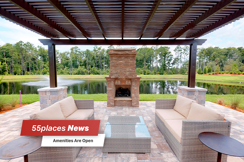 Two couches and a fireplace on a patio overlooking a pond in Del Webb Nocatee of Ponte Vedra, Florida