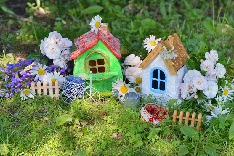 Two miniature houses with garden flowers and summer berries