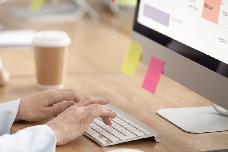 Closeup on the hands of an older woman as she works on a computer