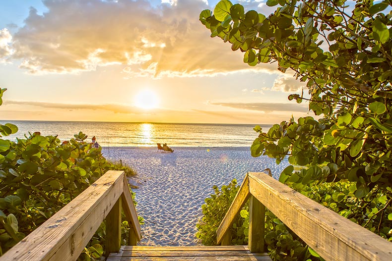 View of a beach beyond a wooden boardwalk at sunset in Naples, Florida