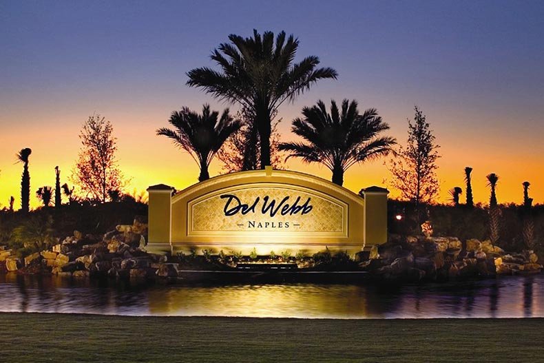 Sunset view of the community sign for Del Webb Naples with palm trees in the background