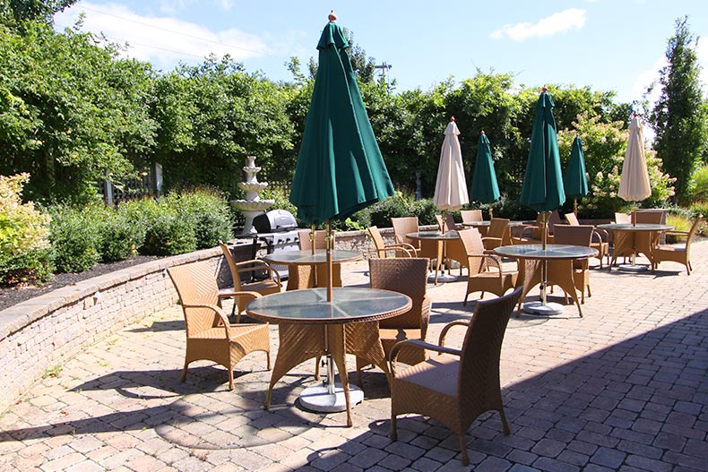 Lounge chairs, tables, and umbrellas on the outdoor patio at Gatherings at Bel Aire Lakes in Absecon, New Jersey