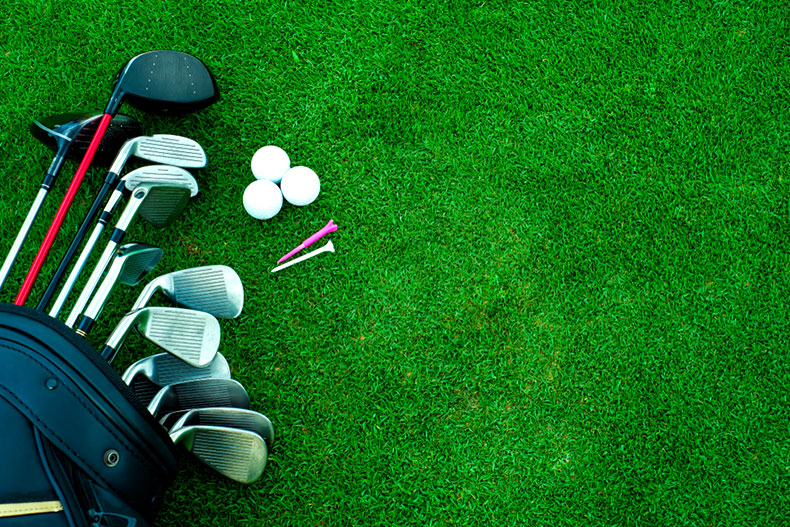 Golf clubs, balls, and tees on the grass of a golf course.