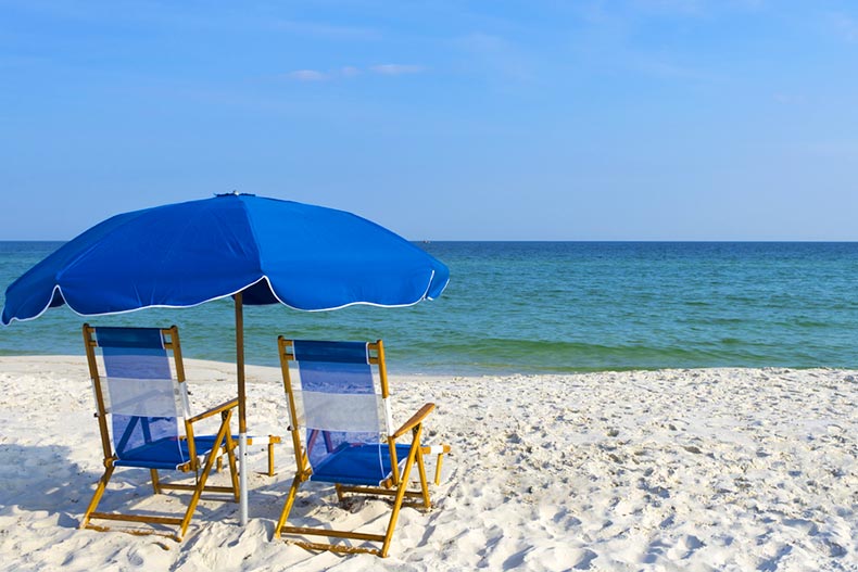 Two beach chairs under an umbrella on a picturesque Gulf Coast beach