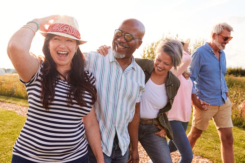 A group of active adult friends smiling and laughing while walking through a nature preserve