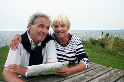 Snowbirds An older adult couple sitting together at a picnic table on the coast while looking at a map