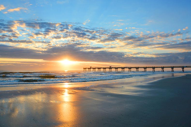 Sun rising over a pier along a beach in Jacksonville, Florida