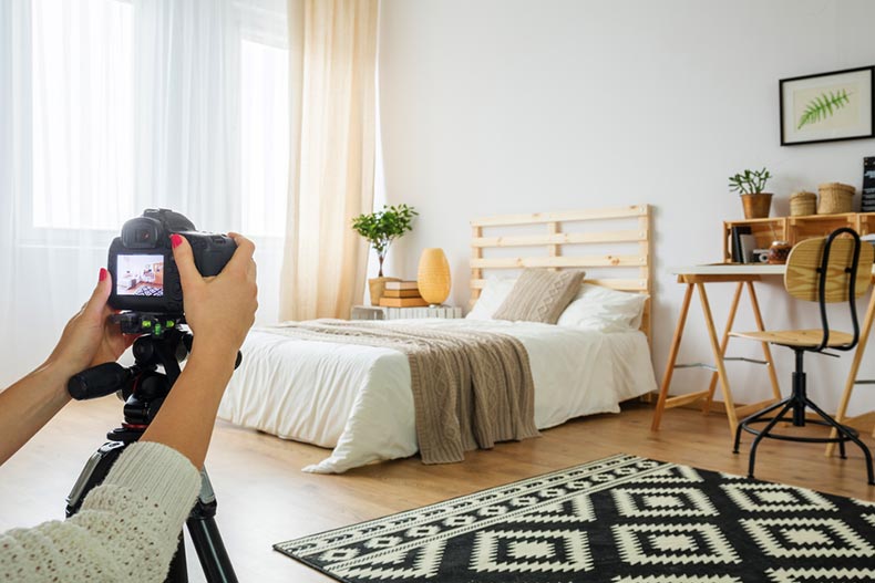 A real estate agent taking a photo of a staged bedroom for a listing