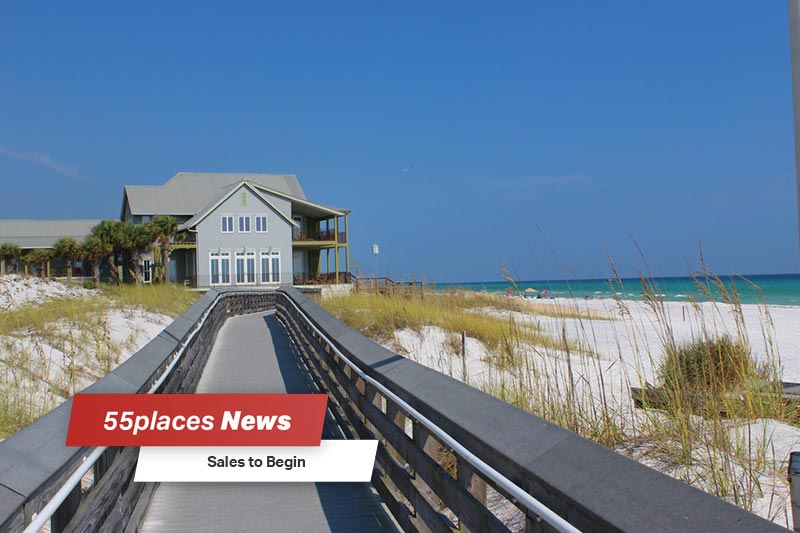 "Sales to Begin" banner over a view down a boardwalk along the beach in Watersound, Florida