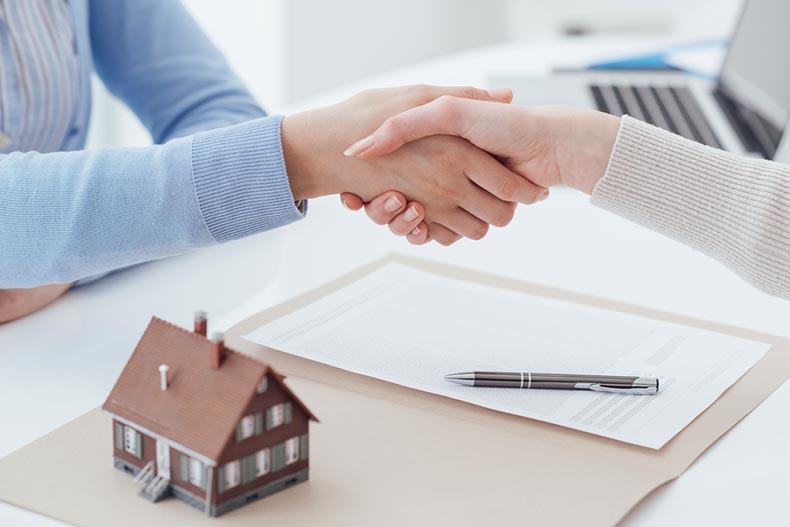 Real estate broker and customer shaking hands after signing a contract