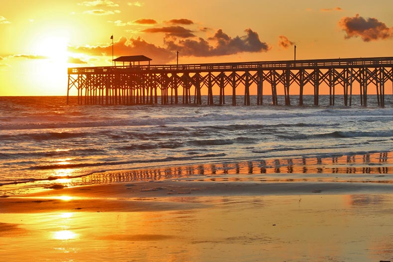 A golden sunrise over a wooden pier along the beach in Myrtle Beach, South Carolina