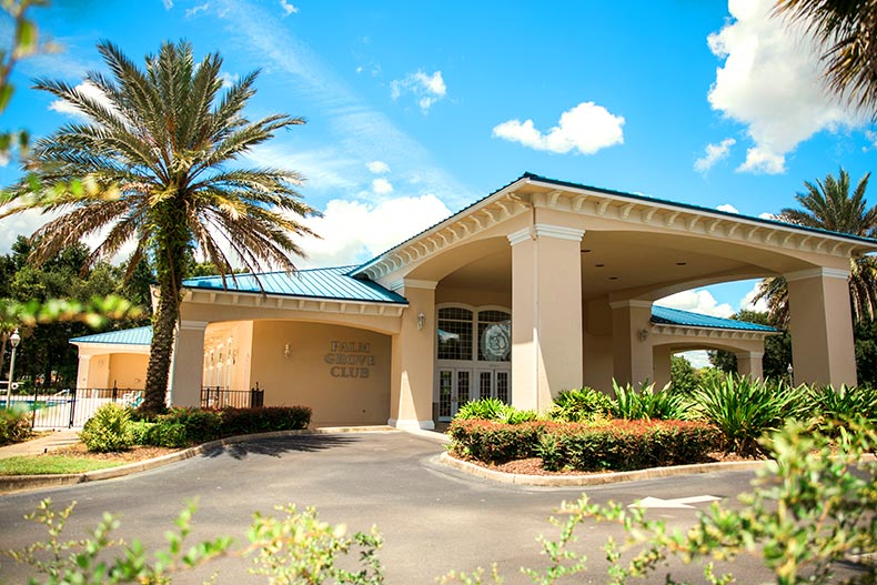 Exterior view of the Palm Grove Club clubhouse in Oak Run surrounded by greenery and a driveway, located in Ocala, Florida
