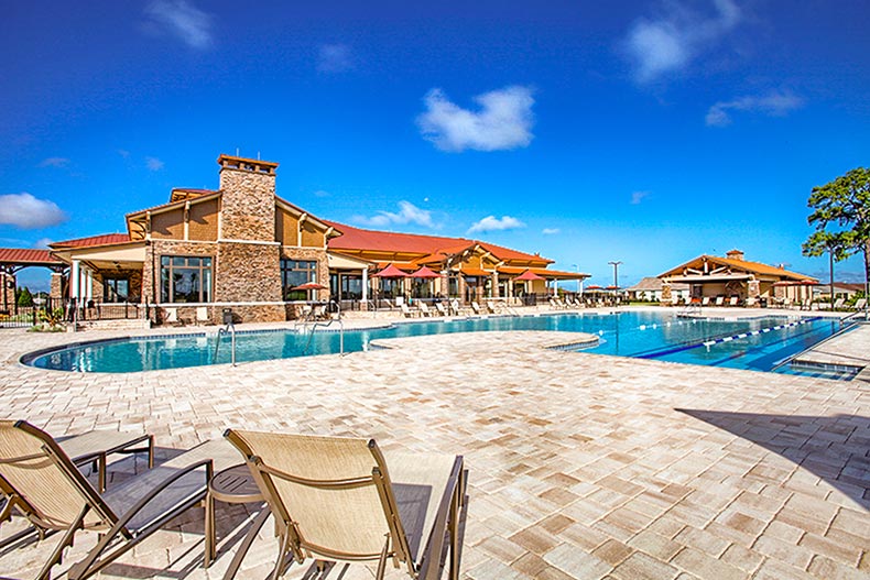 A clubhouse beside an outdoor pool and a patio with lounge chairs at On Top of the World in Ocala, Florida