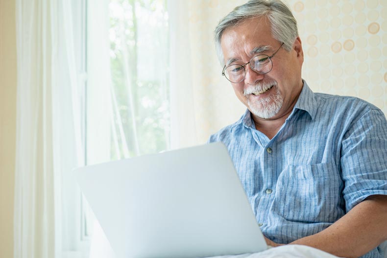 A happy senior man using his laptop to explore new interests and hobbies