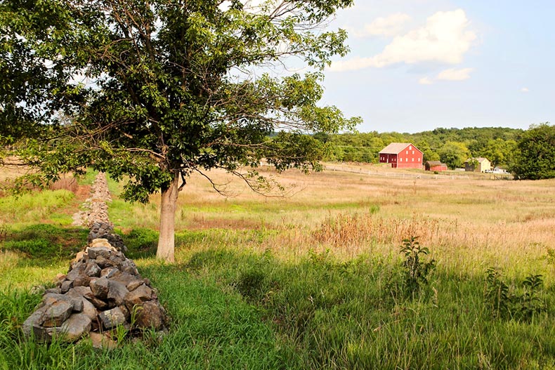 A stone wall, trees, and a red barn in Gettysburg National Military Park in Pennsylvania