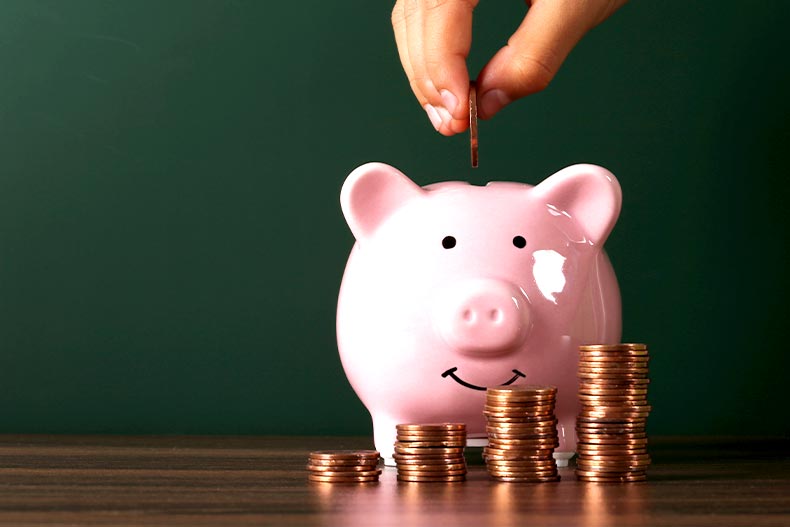 Piggy bank with growth coins against blank dark green chalkboard