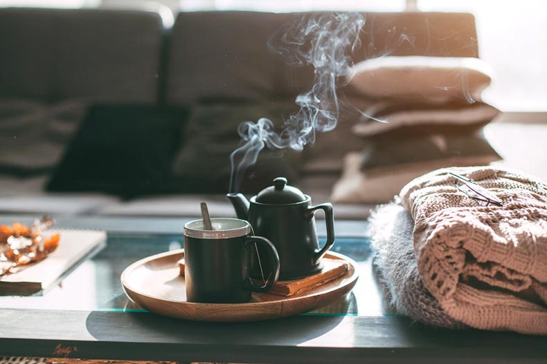 Sweaters and a pot of tea on a coffee table in a cozy home