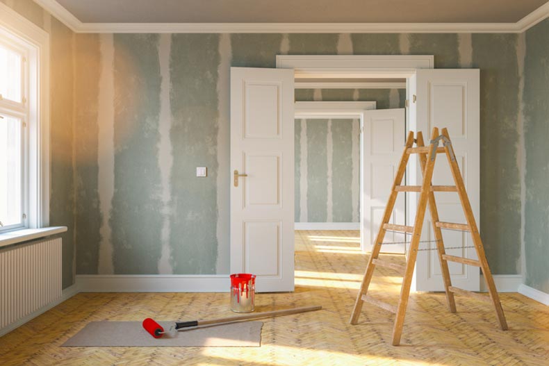 A room being renovated with a ladder and a paint bucket