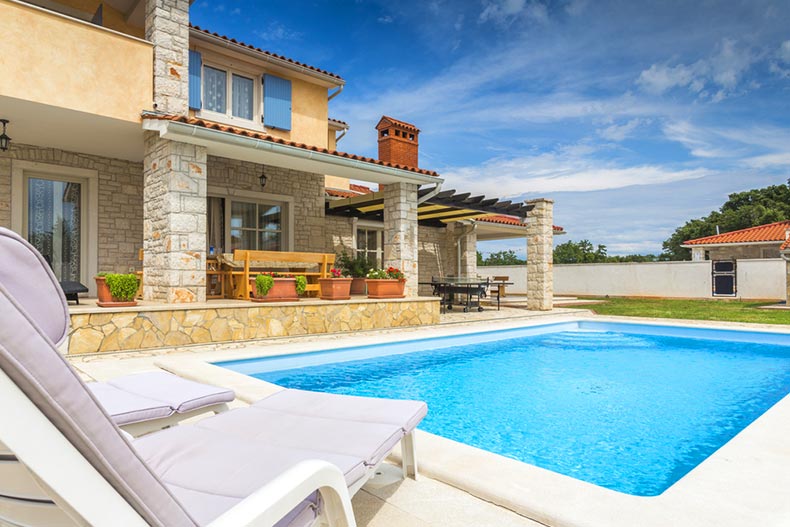 Lounge chairs beside an outdoor pool at a vacation home