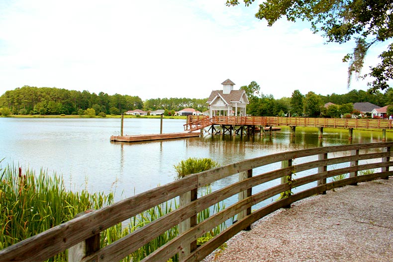 Photo of a pier and gazebo on Lake Somerset in Sun City Hilton Head taken from a pathway with a wooden fence