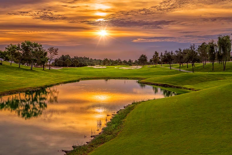 View of a golf fairway and pond at sunset in Sun City Shadow Hills, located in Indio, California