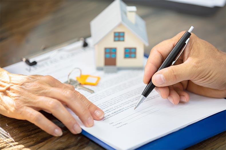 Close-up of a real estate agent's hand helping a client sign a deed