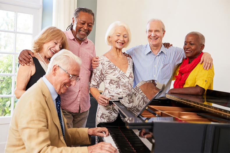 Group of older adults singing around a piano