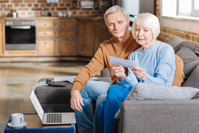 An older woman sitting with her husband while looking over a Social Security document