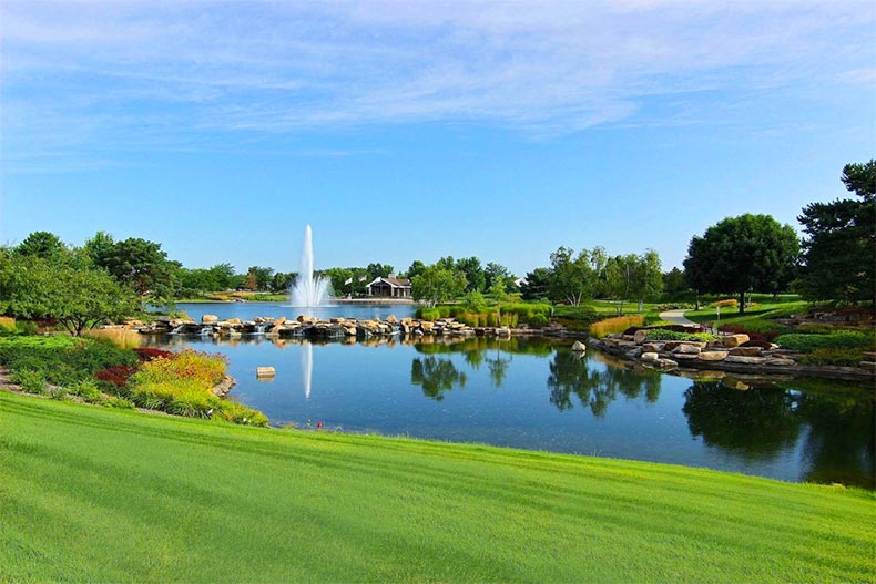 Manicured landscaping surrounding a pond with a fountain at Sun City Huntley in Huntley, Illinois