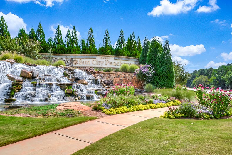 Manicured greenery and a small waterfall beside the community sign at Sun City Peachtree in Griffin, Georgia