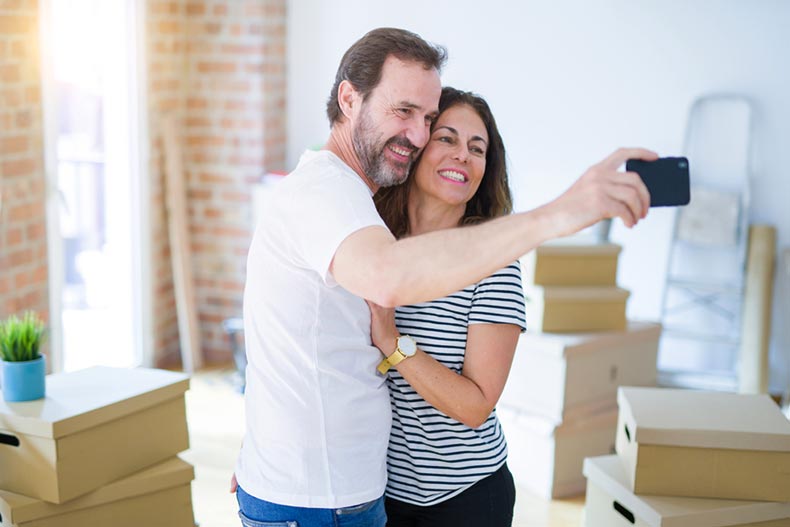 An active adult couple taking a selfie after packing up to move into their dream home
