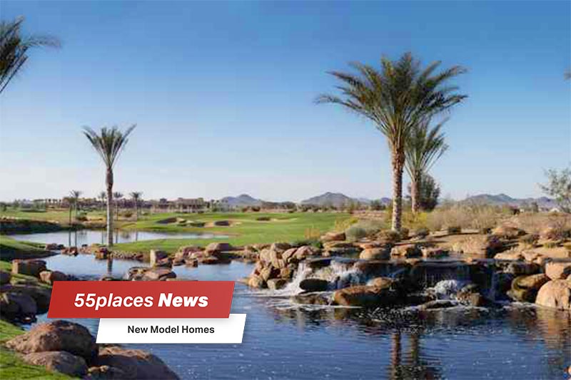 "New Model Homes" banner over palm trees surrounding a pond at Trilogy at Encanterra in Queen Creek, Arizona