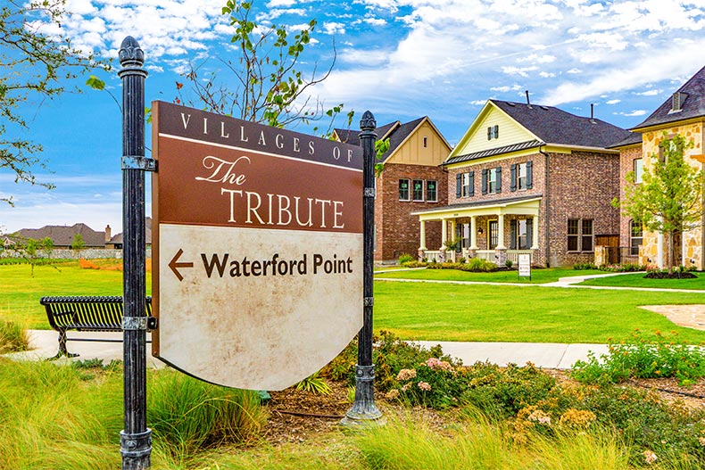 Houses behind the community sign pointing towards Waterford Point at The Tribute in the Dallas-Fort Worth area