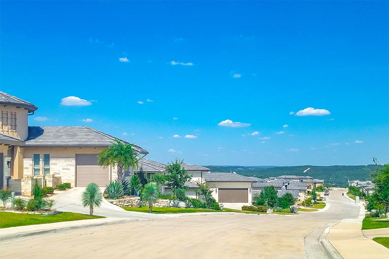 A blue sky over a row of homes lining a street at La Cima at Cresta Bella in San Antonio, Texas