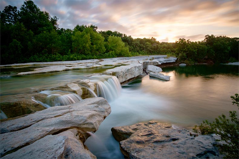 A sunrise over a waterfall at McKinney Falls State Park in Texas
