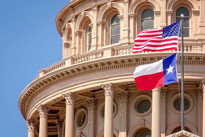 American and Texas flags flying on the dome of the Texas State Capitol building in Austin, Texas