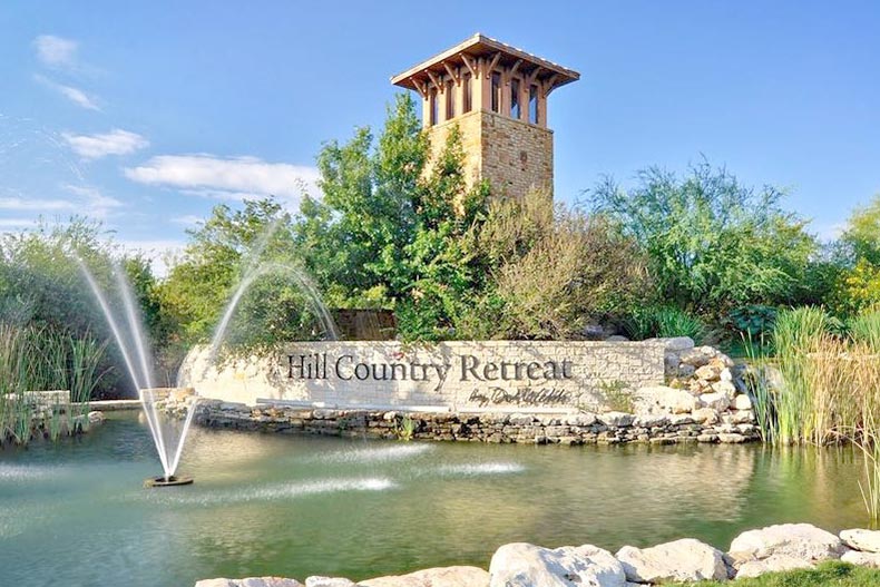 Blue sky over a fountain in front of the sign for Hill Country Retreat in San Antonio, Texas