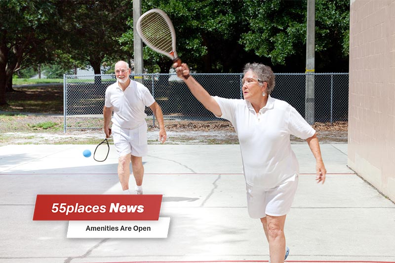 "55places News: Amenities Open" banner over an active senior couple playing racquetball