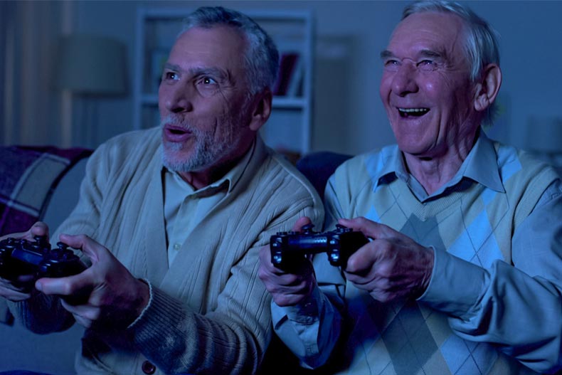 Two older men playing Playstation in a dark room