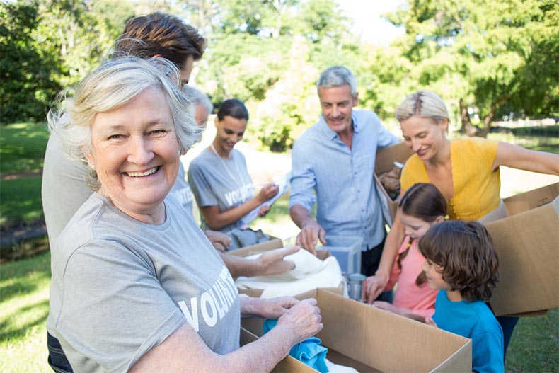A happy senior volunteer helping pack donations into cardboard boxes on a sunny day