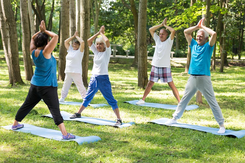 A group of seniors taking a yoga class outside on the grounds of a 55+ community