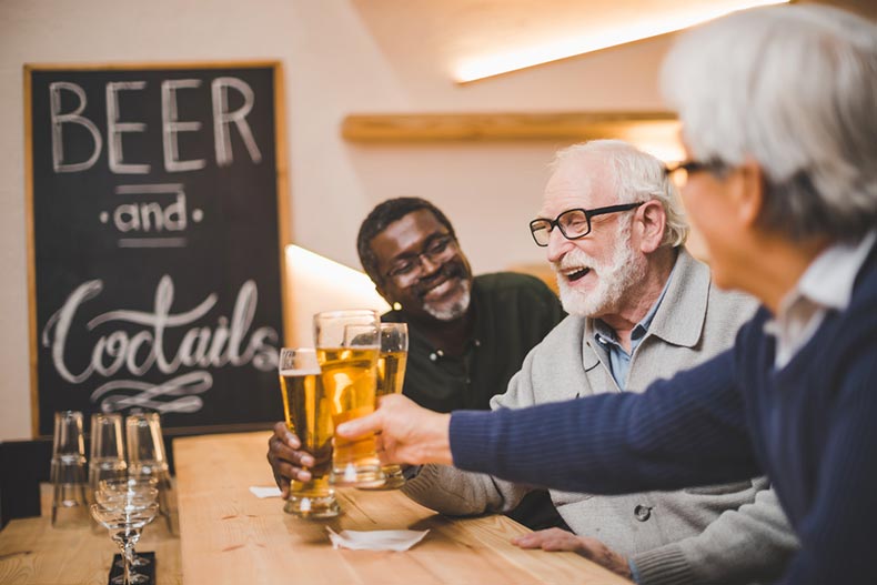 Three senior men laughing and enjoying beers together